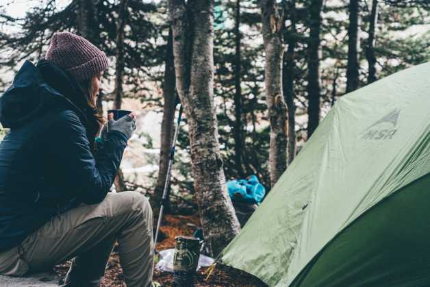 woman camping drinking outside tent