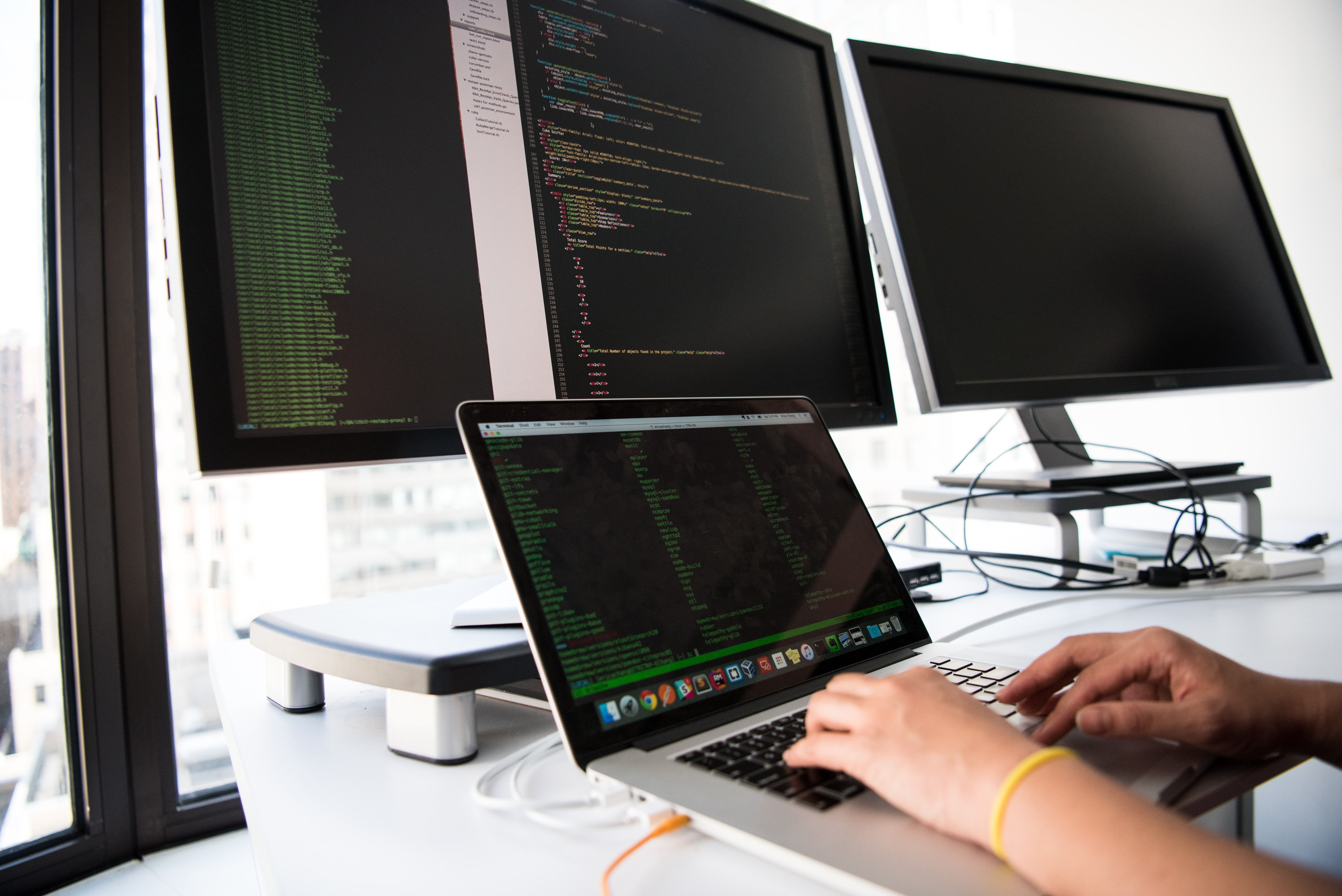 Person writing code on 3 computers