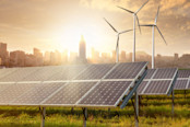 solar panels and wind generators against city view on sunset
