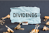 blue paper with clips on a gray background with the text DIVIDENDS