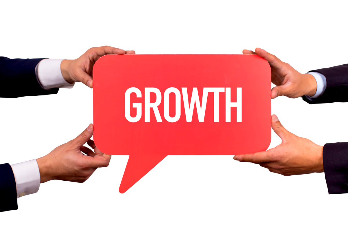 Two men holding red speech bubble with GROWTH message