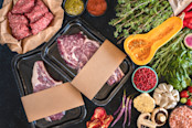 Raw beef meat in the vacuumed skin pack with vegetables on the rustic table.