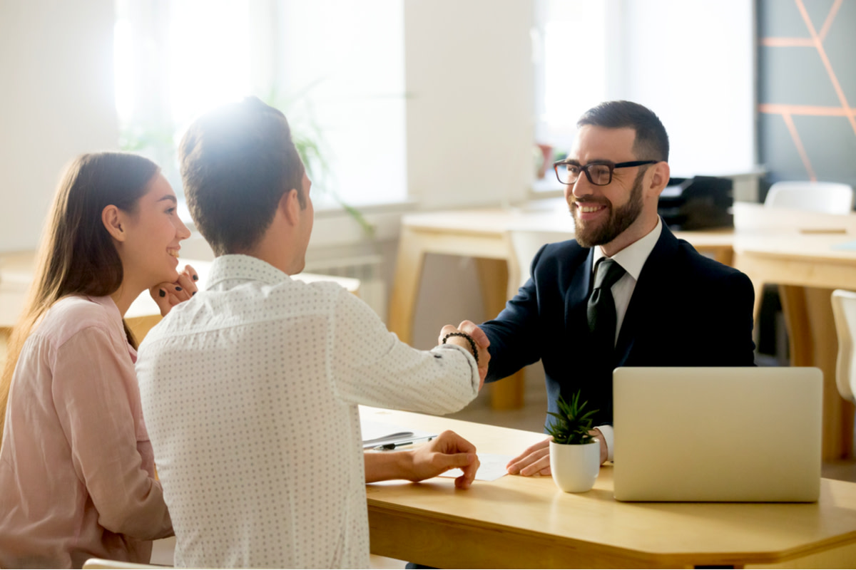 financial advisor handshaking young couple thanking for advice