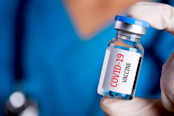 doctor with a stethoscope on shoulder holding syringe