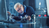Middle Aged Engineer in Glasses Working with High Precision Laser Equipment
