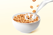A bowl of ring cereals or cheerios with pouring milk splashes.