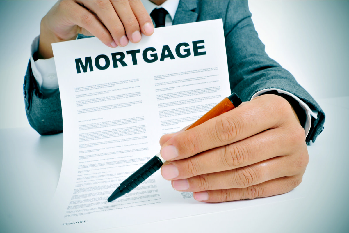 man wearing a suit sitting in a table showing a mortgage loan contract