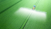 tractor applies herbicides, pesticides or fertilizers to the green field