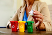 Woman throwing paper into mini recycling bin at office