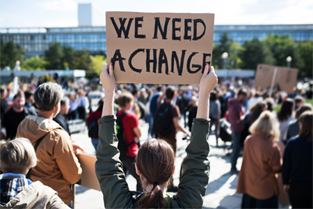 person holding sign that says we need a change