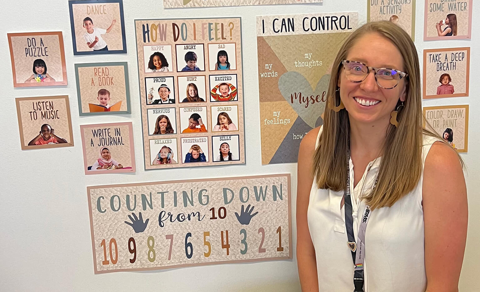 Teacher smiling in front of a bulletin board.