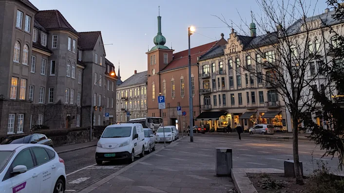 Ullevålsveien i Oslo sett fra St. Hanshaugen ved soloppgang. Knud Knudsens plass nesten tom for mennesker og parkerte biler langs Geitmyrsveien. Den irrgrønne kuppelen på Markus' kirke rett imot.