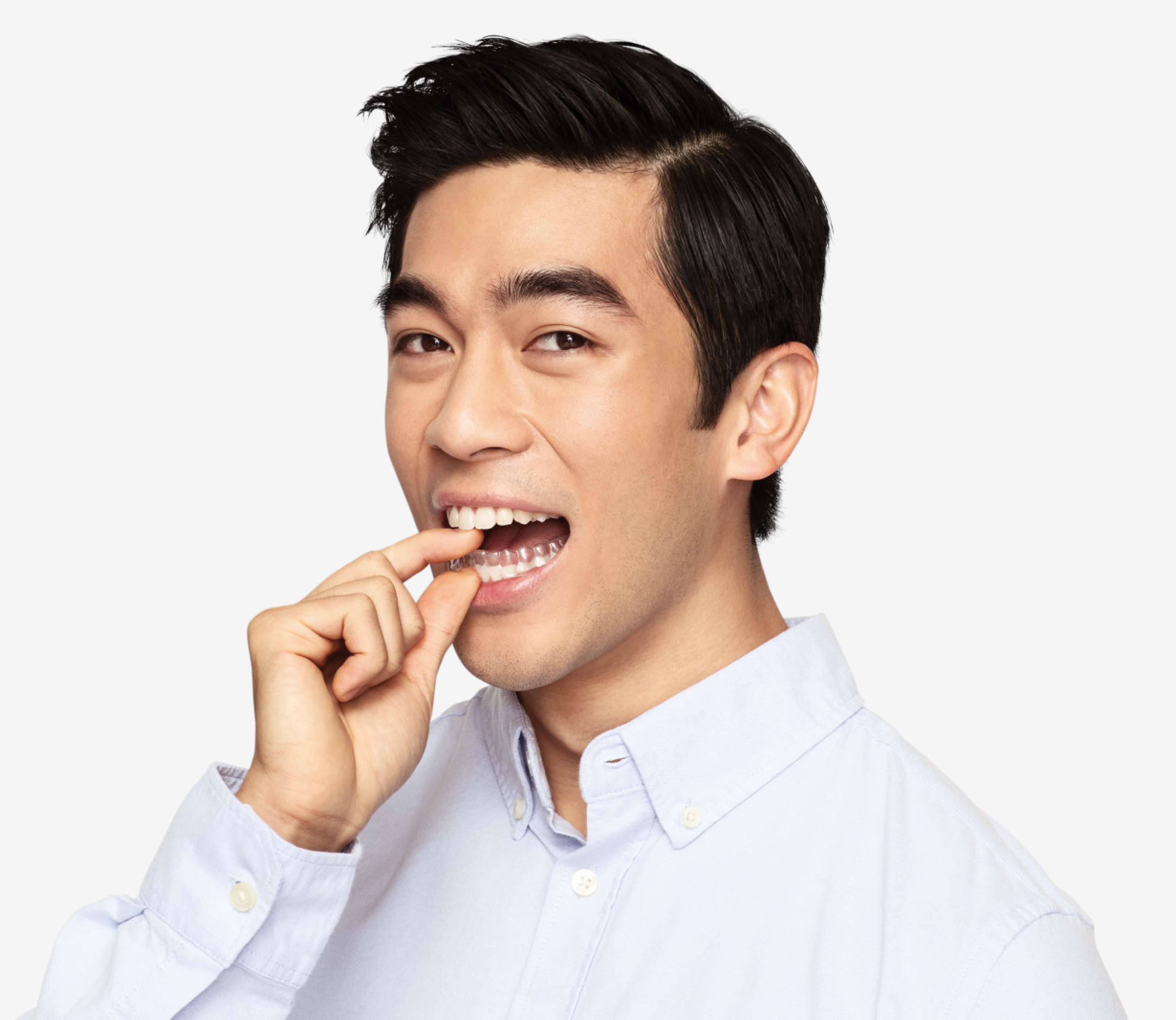 Asian man putting a SmileDirectClub aligner on his lower teeth