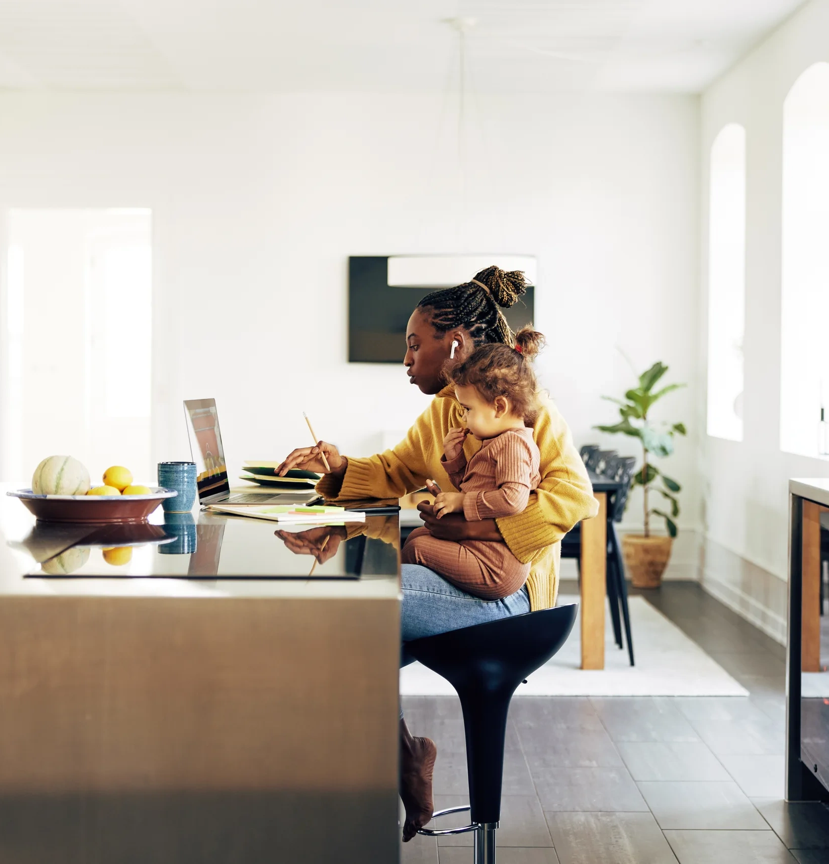 Mother is working at the laptop and holding a child