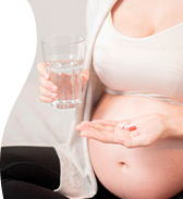 Femibion: mulher segurando um copo de água em uma das mãos e comprimidos de ferro, ácido fólico e outras vitaminas na outra