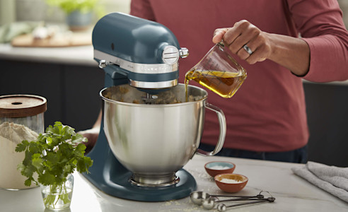 Oil being poured into the bowl of a KitchenAid® stand mixer