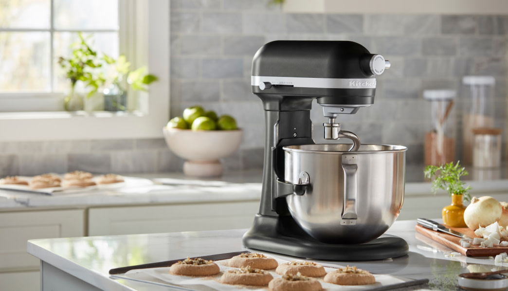 Black KitchenAid® stand mixer on a counter beside a tray of cookies