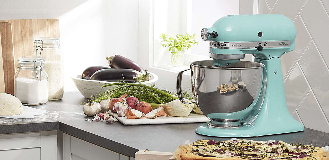 A teal KitchenAid® stand mixer with vegetables on the counter