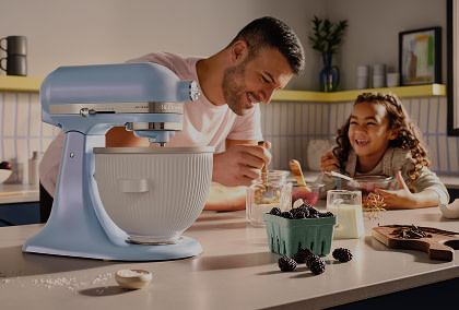 A father and child baking behind a Blue Salt stand mixer.