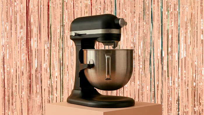 A KitchenAid® bowl-lift stand mixer in front of a shiny decorative background