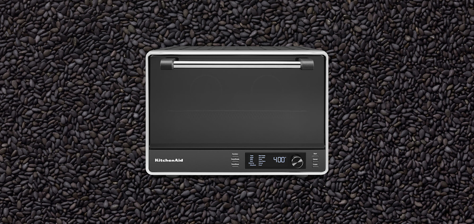 Black KitchenAid® countertop oven set against a background of black sesame seeds