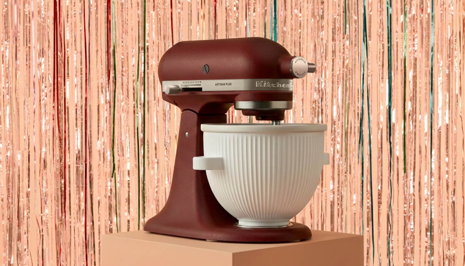 A KitchenAid® stand mixer and ice cream maker attachment in front of a shiny decorative background
