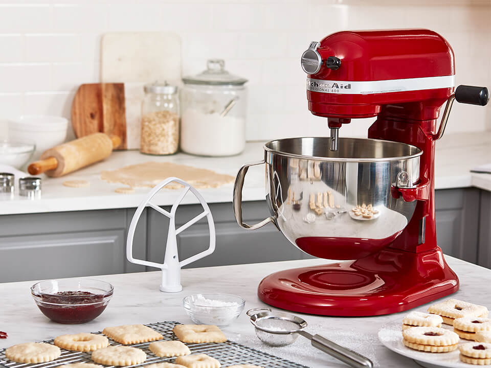 A red bowl-lift stand mixer with a flat beater attachment.