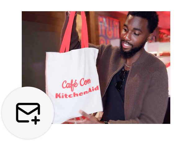 A person holding a white tote bag with KitchenAid branding