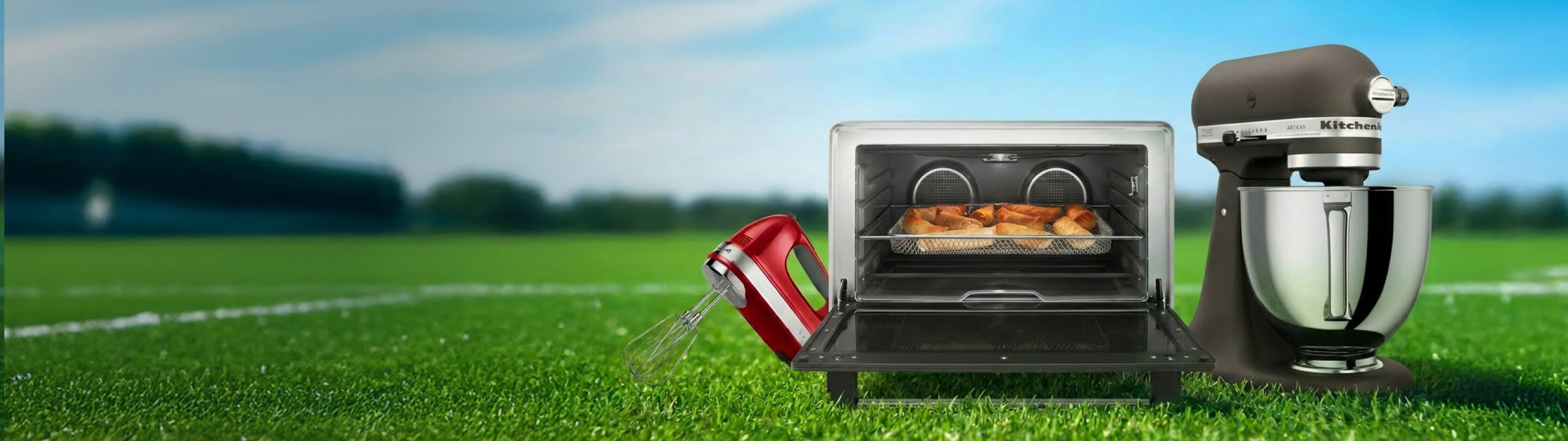 A KitchenAid® hand mixer, stand mixer and countertop oven on a soccer field