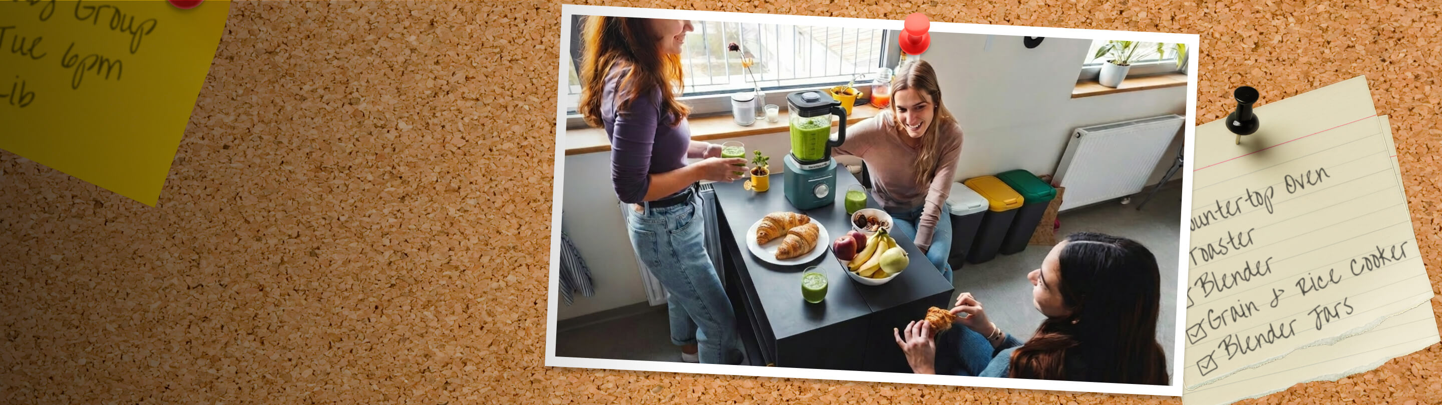 A corkboard with a picture of Friends sitting around a table with a KitchenAid® blender and breakfast food