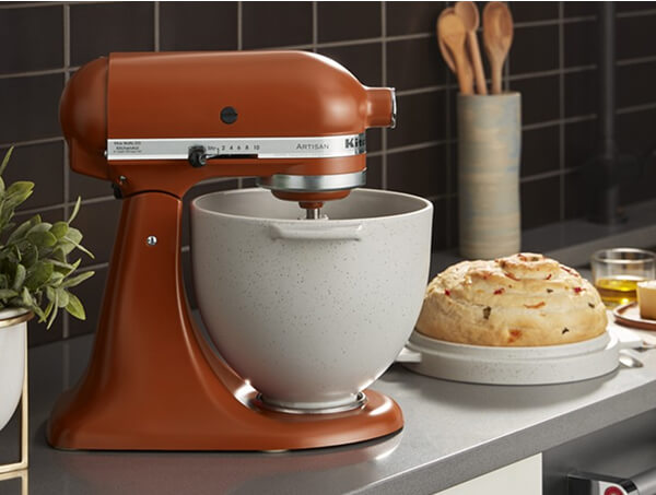 Orange KitchenAid® stand mixer with a ceramic bowl beside a loaf of bread