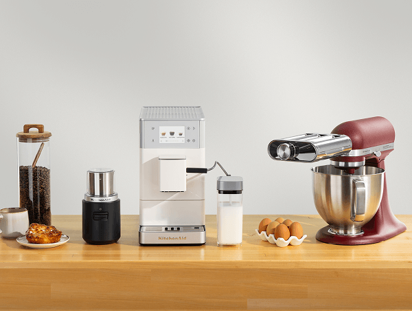 KitchenAid® espresso machine, coffee grinder, and burgundy stand mixer with a pasta roller attachment on a wood counter