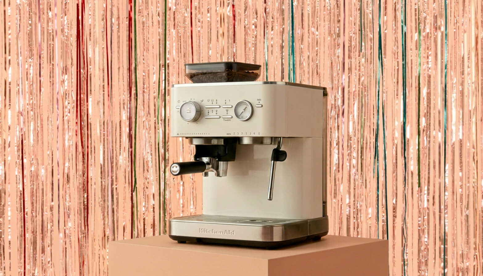 A KitchenAid® semi-auto espresso machine in front of a shiny decorative background