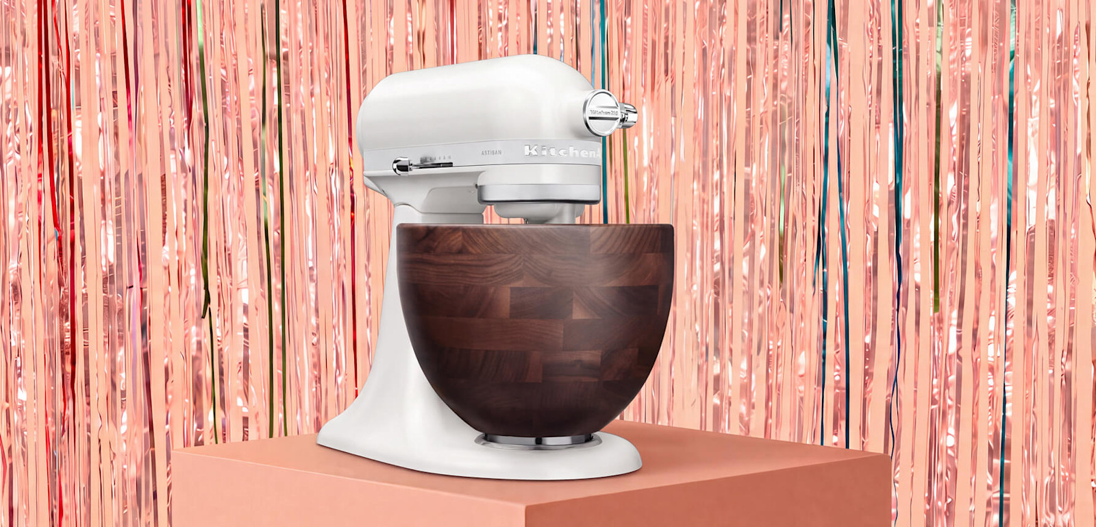 A KitchenAid® stand mixer against a pink tinsel background.