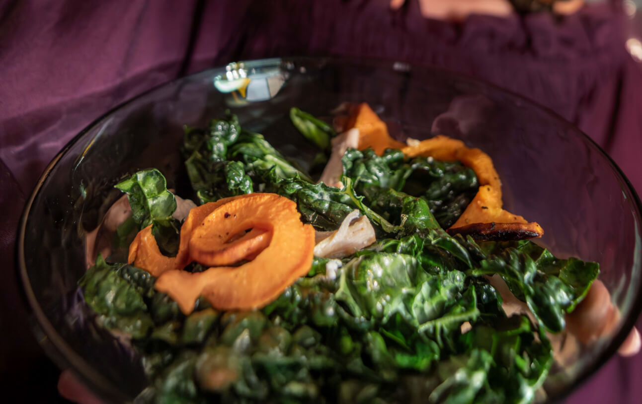Kale salad topped with spirlized squash in a glass bowl