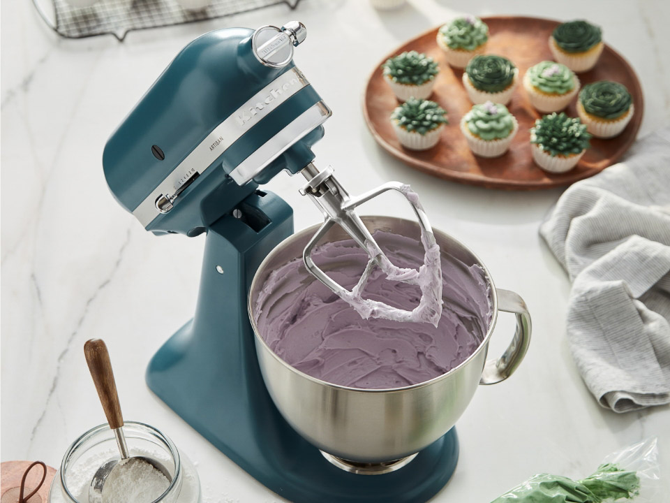 A tilt-head Artisan stand mixer mixing ingredients for muffins.