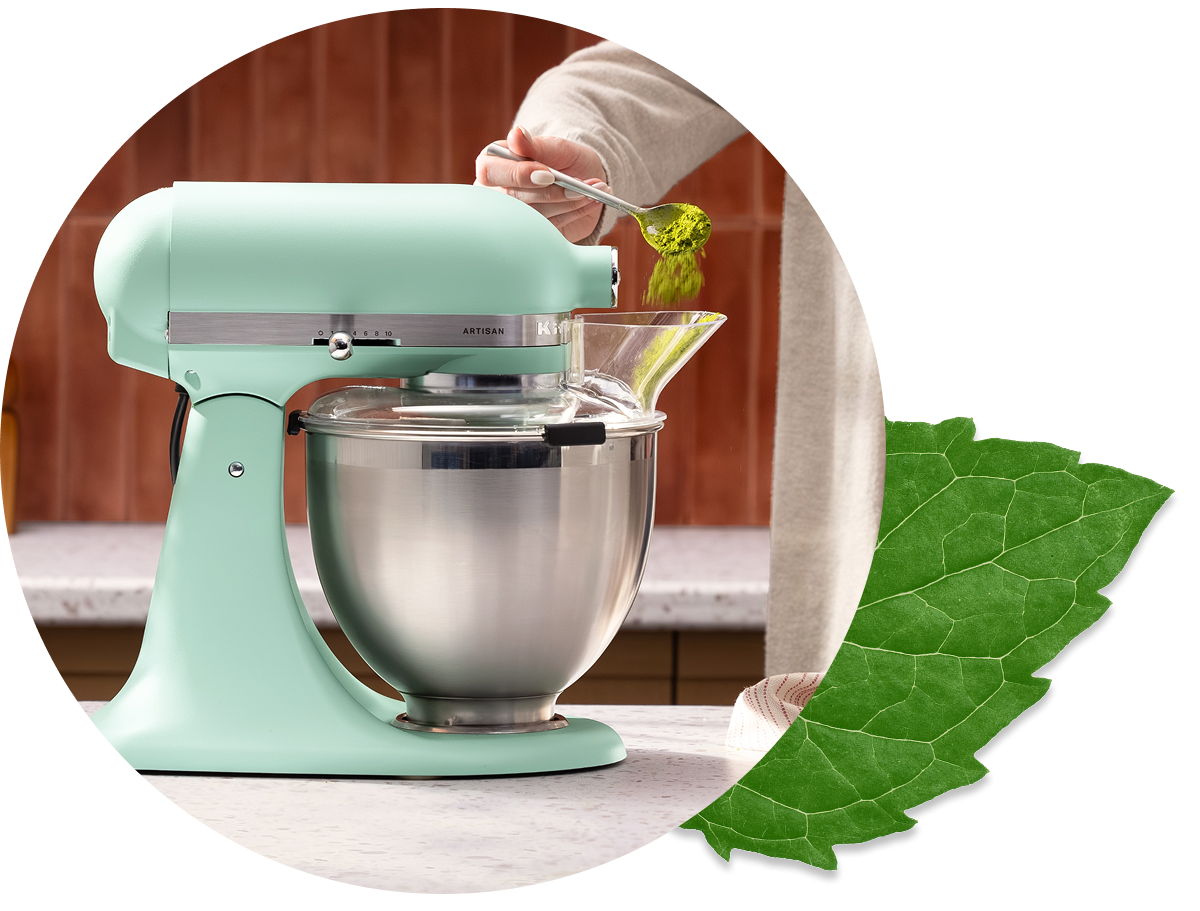 A person adding matcha powder into the mixer using the bowl lip.