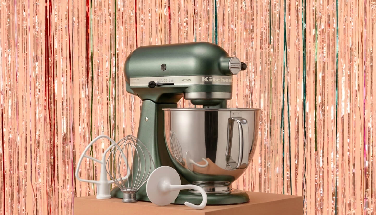 A KitchenAid® stand mixer with accessories in front of a shiny decorative background