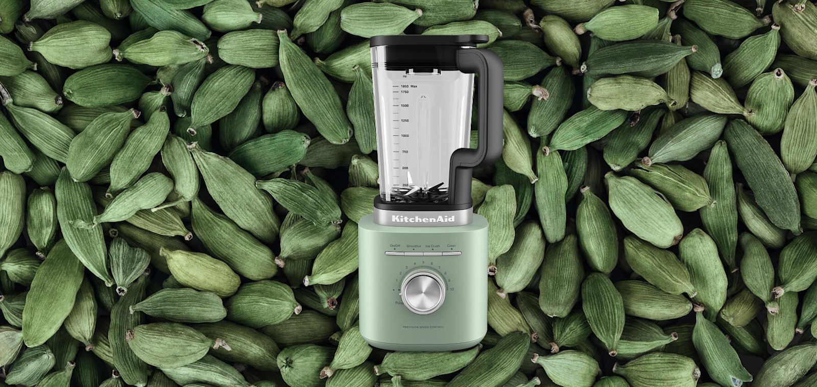 Green KitchenAid® blender set against a background of green cardamom pods
