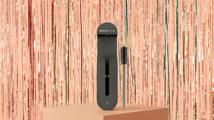 A KitchenAid® smart thermometer in front of a shiny decorative background