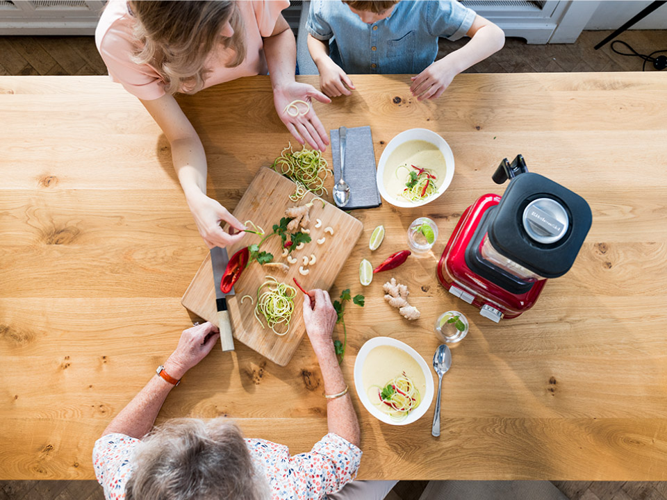 A family using a blender to prepare fresh ingredients.