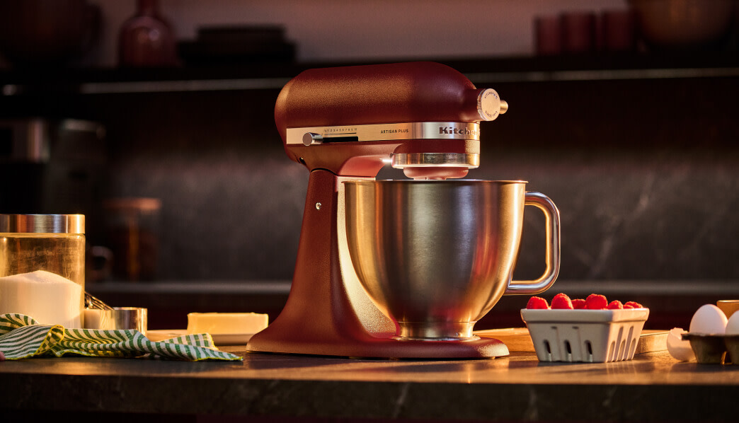 KitchenAid® Artisan Plus stand mixer on a counter beside a carton of raspberries