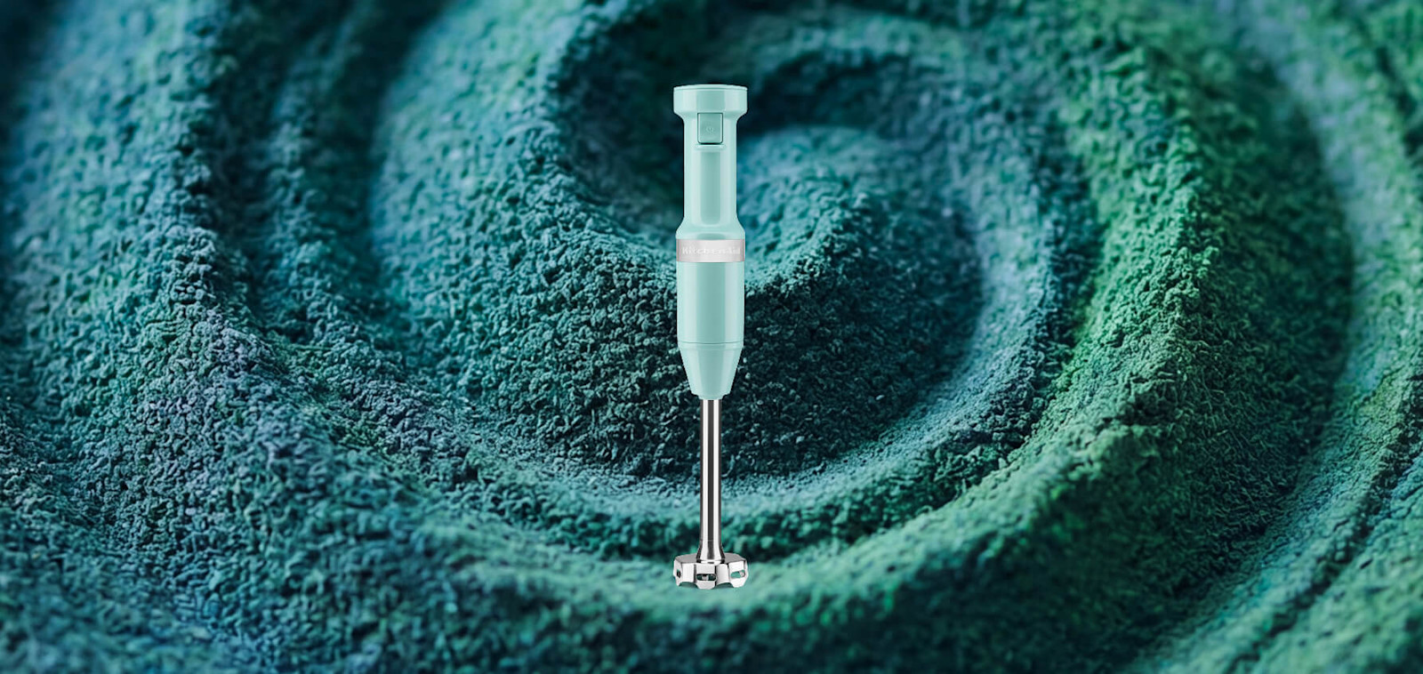 Teal KitchenAid® immersion blender set against a swirled spirulina background