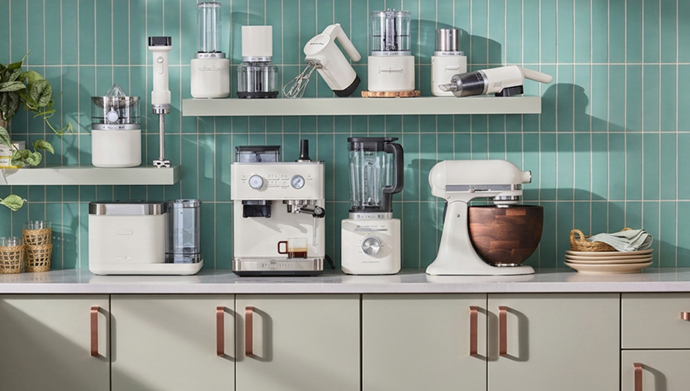 KitchenAid® appliance collection in white, including a stand mixer with walnut bowl, espresso machine, kettle, and toaster