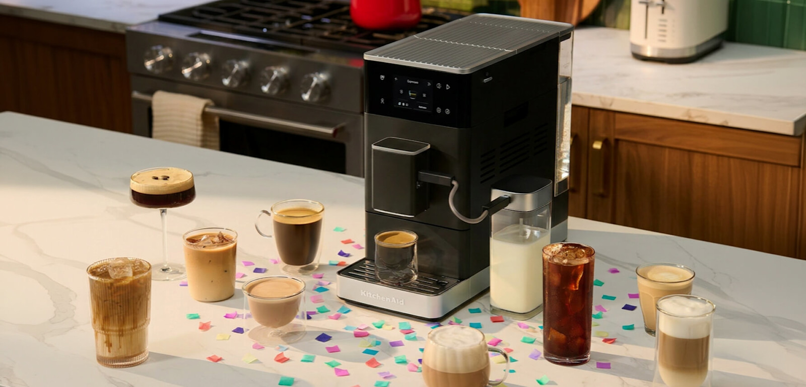 A KitchenAid® espresso machine surrounded by coffee drinks and confetti