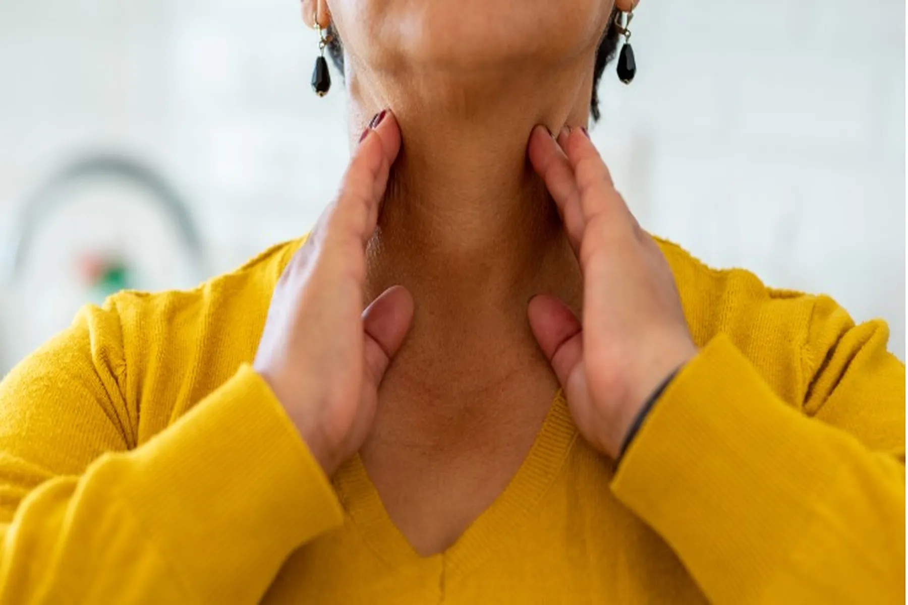 Woman touching her sore throat.