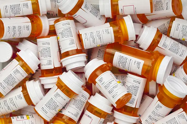 A pile of prescription medications in orange pill bottles.