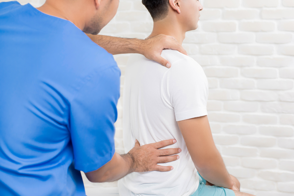 A healthcare professional assesses and/or works on the back of a client.