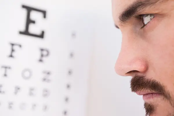 A man is looking into an eye exam chart.