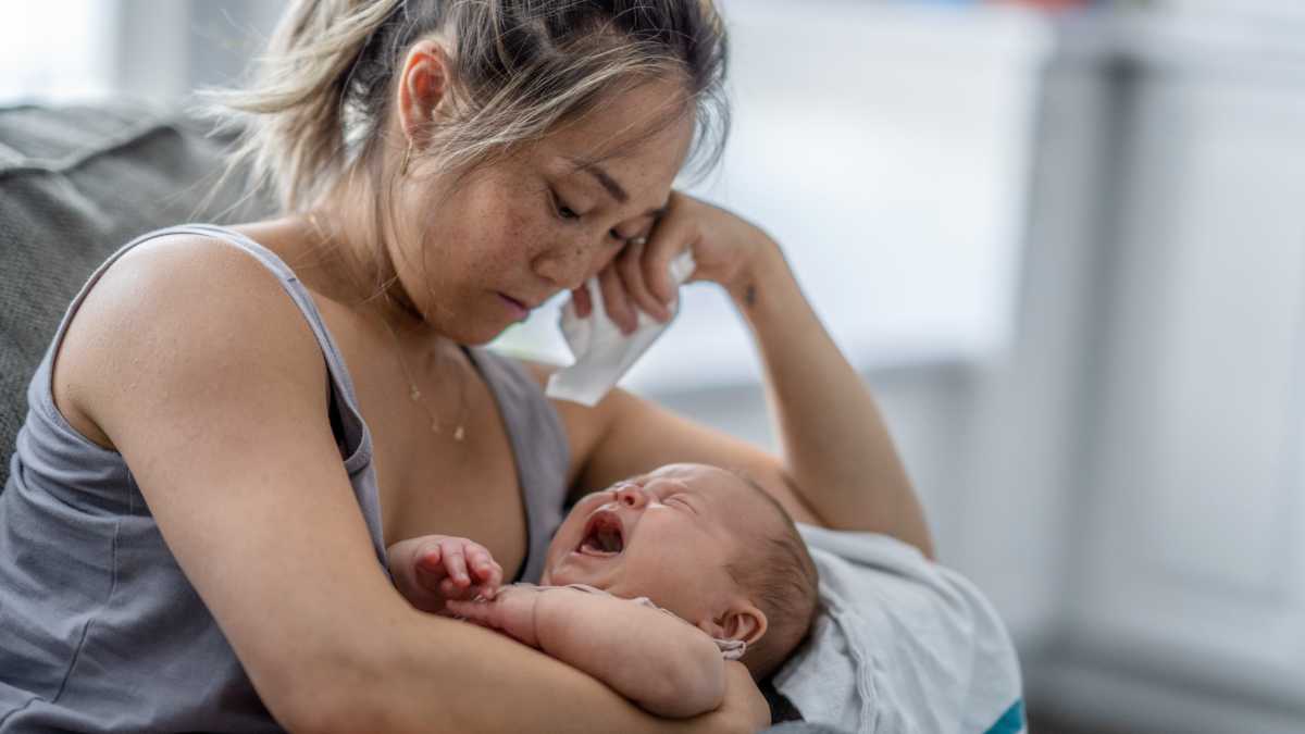 tired and sad mom holding newborn